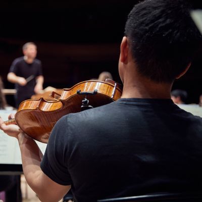 Viola player looking on at the conductor in a rehearsal
